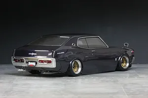 Rear-quarter studio shot of a dark purple Pandora RC C130 Laurel drift body shell mounted on a chassis with gold mesh wheels.