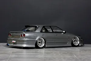 Rear three-quarter view of a painted grey Pandora RC ER34 Skyline 4-door drift body shell on a studio floor with dark background.