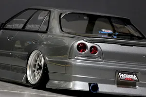 Close-up rear angled view of a grey ER34 Skyline RC drift car body showing custom deep dish wheels, exhaust, and Pandora RC decals.