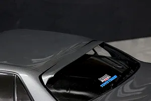 Close-up of a grey RC car body roof and rear window showing a roof spoiler and brand decals.