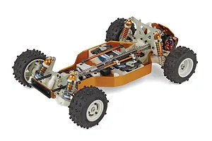 High angle studio shot of the Team Associated RC10 4WD RC buggy chassis showing the chain drive system, gold shocks, and knobby tires on white wheels.