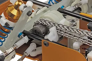 Close-up studio view of the chain drive system and suspension components on the Team Associated RC10 buggy kit.