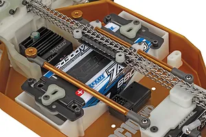 Close-up of the internal chassis of the Team Associated RC10 4WD buggy showing metal drive chains, battery, and electronics.