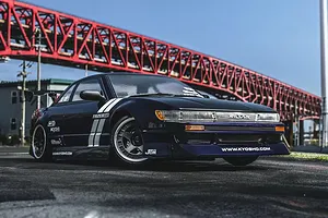 Kyosho Fazer D2 Nissan S13 Silvia RC drift car in purple parked outdoors under a large red metal bridge.