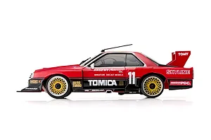 Side profile of the Kyosho First Mini-Z 1982 Nissan Super Silhouette RC car in red and black with gold mesh wheels and racing livery.