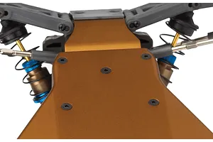 Close-up view of the bronze anodized aluminum chassis and front suspension components of an RC buggy.