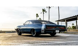 Kyosho Fazer MK2 1970 Dodge Charger RC car parked outdoors on a paved lot with palm trees in the background.