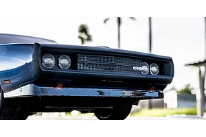 Close-up lifestyle shot of the front grille and headlights of the blue Kyosho 1970 Dodge Charger RC car outdoors.