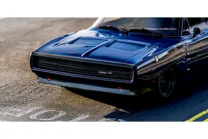 Close-up lifestyle shot of the front grille and hood of the blue Kyosho 1970 Dodge Charger RC car parked on asphalt.