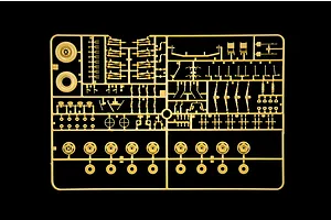 Tan plastic model sprue featuring various vehicle suspension and wheel parts on a black background.