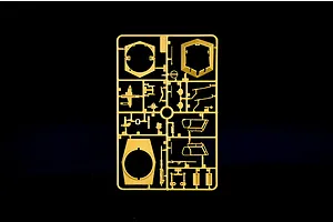Tan plastic model kit sprue containing various parts and turret components on a black background.