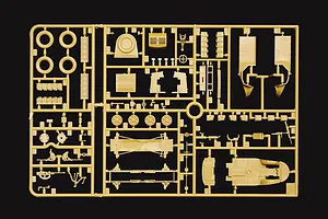 Tan plastic model kit sprue containing unassembled vehicle parts, wheels, and equipment against a black background.