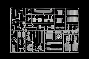 Grey plastic model kit parts sprue featuring truck parts like engine components, tanks, and structural elements on a black background.