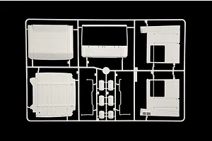 White plastic model kit sprue featuring truck cab panels and small accessory parts on a black background.