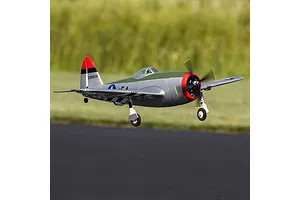 Micro P-47 Thunderbolt RC warbird in flight just above an asphalt runway with green grass backdrop.