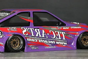 Side view of a purple RC drift car body featuring Ted Arts sponsor decals and gold mesh wheels.
