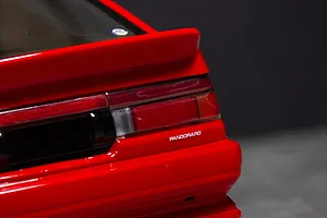 Close-up of the rear tail light and spoiler on a red RC model car body against a dark background.