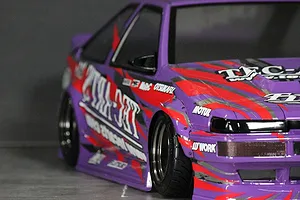 Close-up of a purple RC drift car body featuring Ted Arts and other sponsor decals applied along the side and hood.