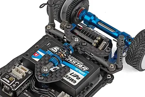 Close-up view of the internal chassis layout of a small scale RC car featuring a blue aluminium motor mount, carbon fiber shock tower, and installed electronic speed controller.