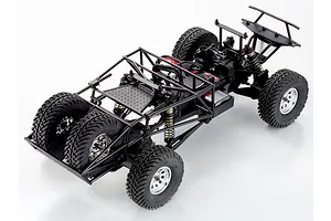 High angle studio view of the RC short course truck chassis without a body, showing its roll cage, spare tires, and suspension setup.