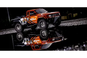 Kyosho Outlaw Renegade 2RSA RC short course truck parked by a puddle reflecting the vehicle in the dark.