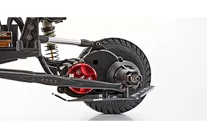 Close-up studio shot of the rear suspension, red anodized motor, and treaded tire on the Kyosho Outlaw Renegade RC truck.