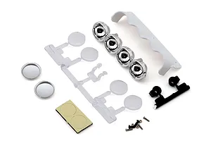 RC car scale accessory parts including chrome light buckets, clear plastic tree, white wing, screws, and adhesive pads on a white background.