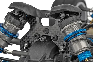 Close-up of the carbon fiber shock tower and blue aluminum dampers on the Team Associated RC buggy.