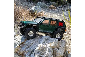 Green Axial SCX10 III Jeep Cherokee XJ RC rock crawler driving over rocks in an outdoor setting.