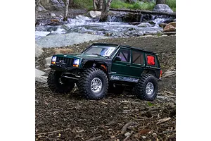 Axial SCX10 III Jeep Cherokee XJ RC rock crawler in green navigating an outdoor rocky stream bed.