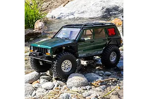 Axial SCX10 III Jeep Cherokee XJ RC rock crawler driving outdoors over rocks and through water.
