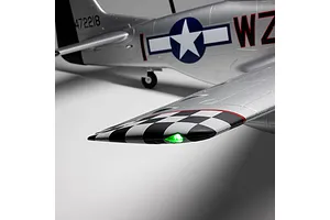 Close-up of the silver P-51D Mustang RC airplane wingtip showing a glowing green light and black-and-white checkered pattern.