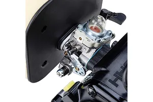 Close-up studio view of a petrol engine carburetor with primer bulb, air filter housing, and adjustment screws.