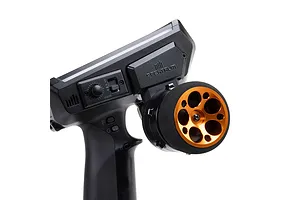 Close-up of a Spektrum RC transmitter installed with an orange aluminium wide circle wheel accessory against a white background.
