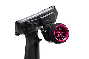 Close-up of a black RC transmitter with a bright pink wide spoke aluminium steering wheel and foam grip on a white background.