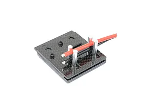 Carbon fibre self-clamping soldering jig holding red and black electrical wires between metal posts against a white background.