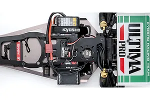 Top-down studio shot of the electronics layout and chassis deck of the Kyosho Ultima Pro RC buggy.