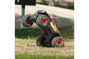 ARRMA Quake 4S RC Monster Truck pulling a wheelie on grass outdoors