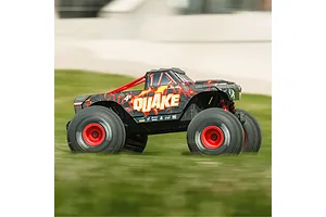 ARRMA Quake 4S RC monster truck driving fast across a grassy field in an outdoor action shot.