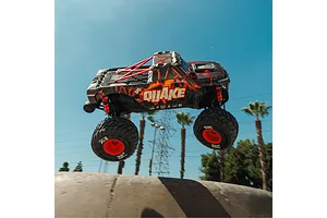 ARRMA Quake 4S RC Monster Truck jumping in the air outdoors against a blue sky with palm trees.