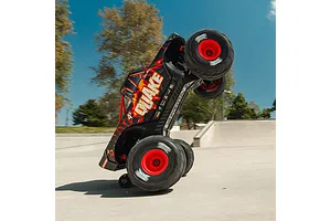 ARRMA Quake 4S RC monster truck performing a vertical wheelie on a concrete skatepark ramp outdoors.