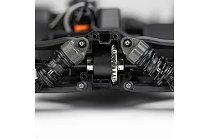 Close-up of RC car front differential housing with exposed metal ring gear and suspension arms on white background.