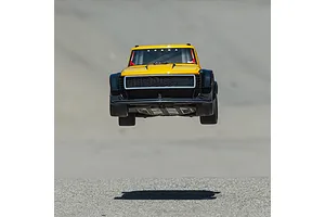 ARRMA Infraction 3S yellow RC street bash car jumping in the air over an asphalt surface.