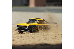 Yellow ARRMA Infraction 3S RC truck kicking up dirt and gravel during outdoor action driving.