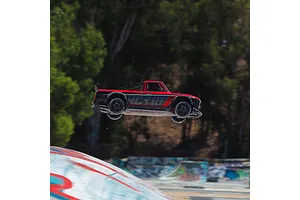 ARRMA Infraction Grom 3S RC car airborne outdoors after launching from a ramp.