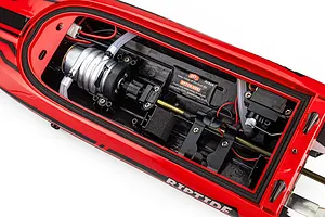 Top down studio view of the interior hull of the Atrek Riptide red RC speed boat, showing the motor, water cooling lines, and steering servo.