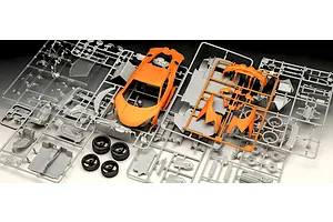 Unassembled plastic model kit parts for a Revell Lamborghini Revuelto, featuring orange body panels, grey components, and rubber tyres.
