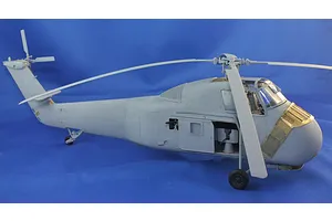 Assembled plastic model of an H-34 helicopter in light grey with brass photo-etch details against a blue background.