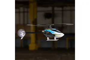 Blade Revolution 155 CP RC helicopter in flight against a dark indoor background.