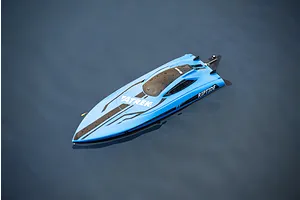 Blue Atrek Riptide RC speed boat floating on calm water, showing top hull design with black graphics and water droplets.